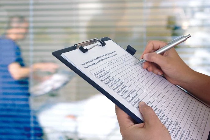 Person geht in einem medizinischen Raum eine Checkliste durch